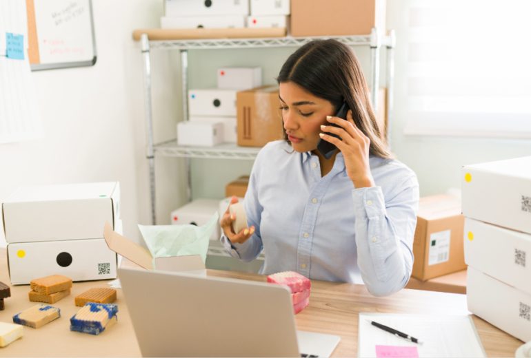 female-business-owner-entrepreneur-talking-phone-with-customer-while-preparing-packages-with-natural-beauty-products-ship (1)